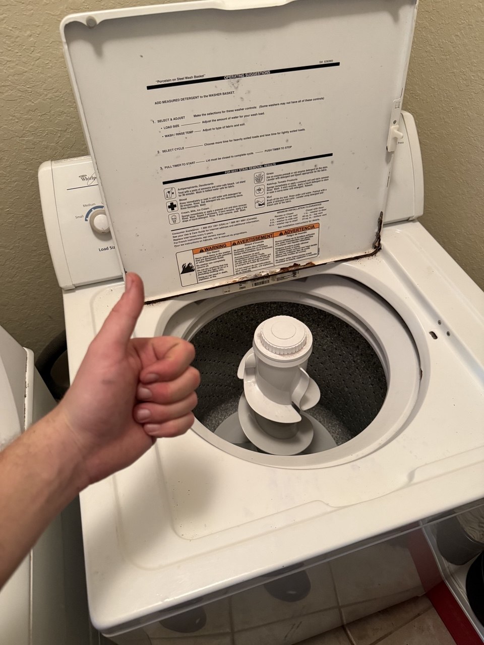 Whirlpool washer opened for repair with technician giving a thumbs up in a Naples home